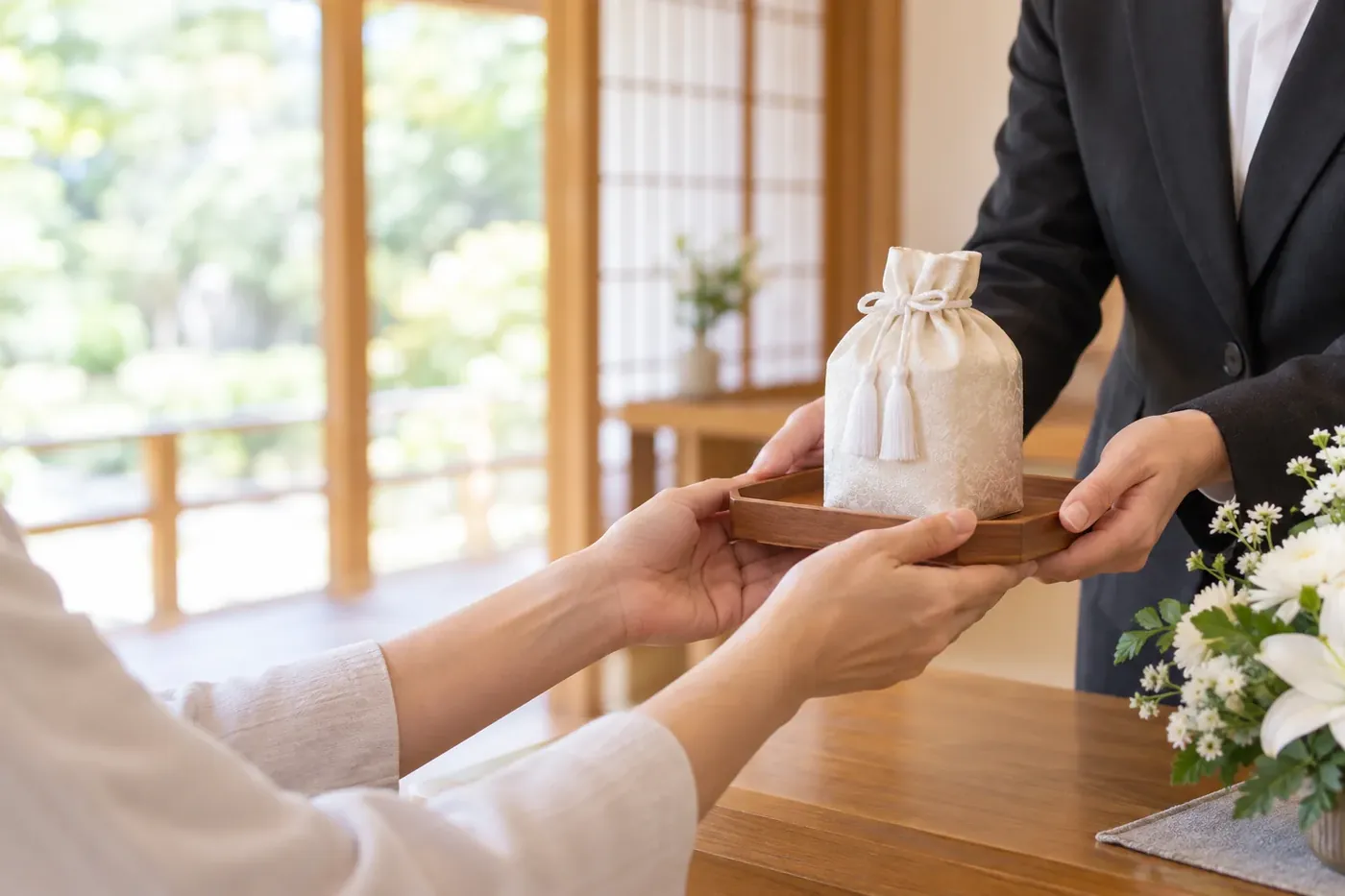 袋に納めた骨壺をご家族へお渡しする手元