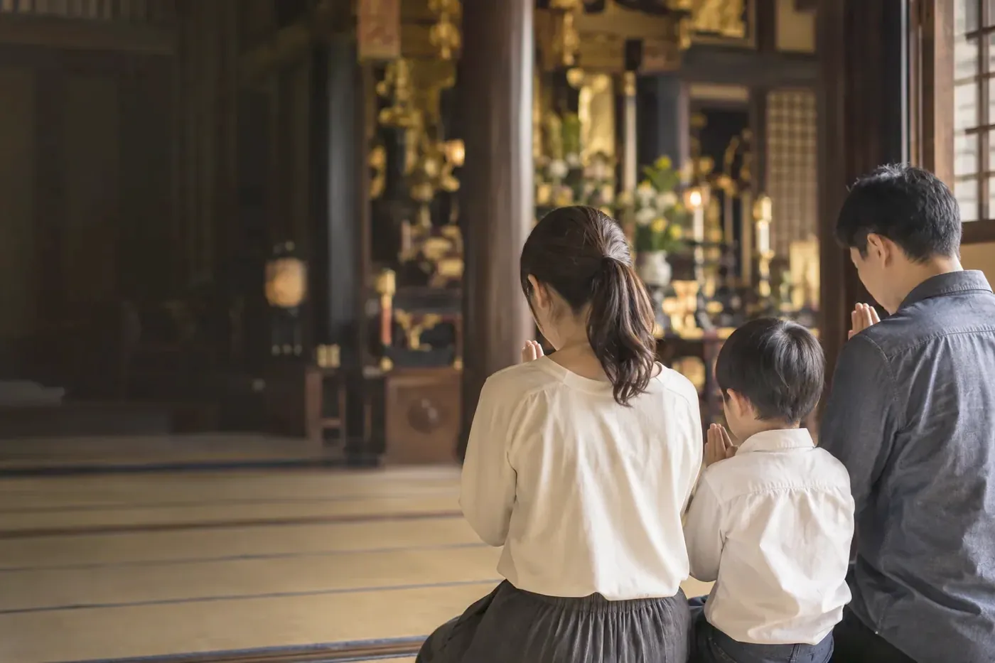 本堂で並んで手を合わせるご家族の後ろ姿